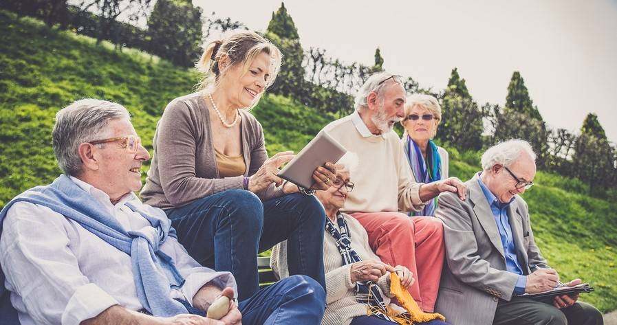 five old people sitting on a grassy knoll, three men two women