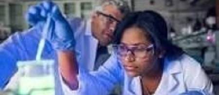 Teacher looking at student dropping liquid into a beaker with an eyedropper