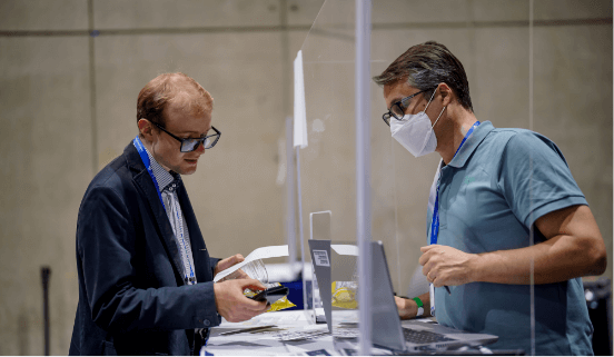 a man giving his meeting registration to another man